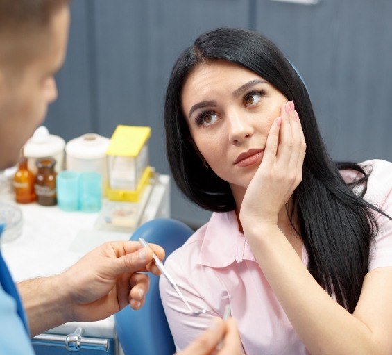 Dental patient holding her cheek in pain