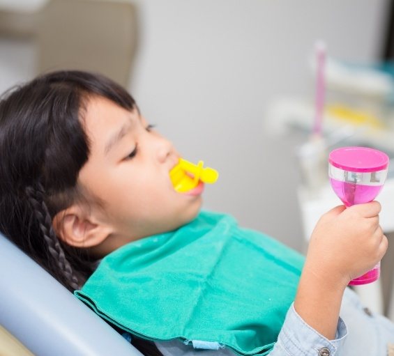 Young girl in dental chair with fluoride trays on her teeth