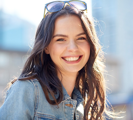 A happy, smiling woman standing on a summery city street 