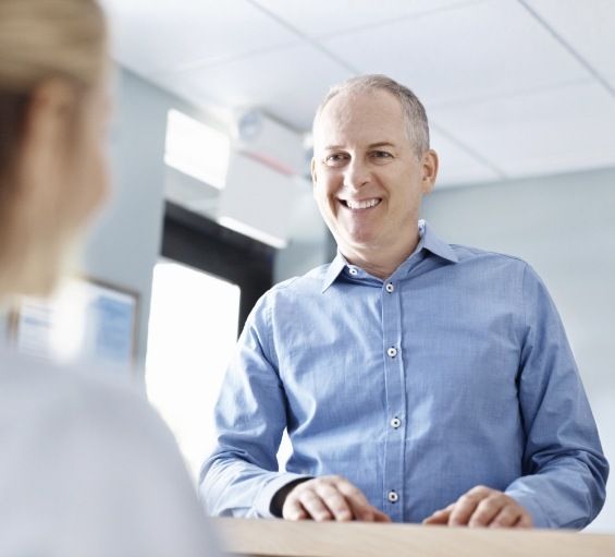 Man smiling at dental office receptionist