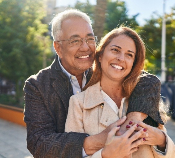 Man holding woman outdoors and smiling with dental implants in Windham