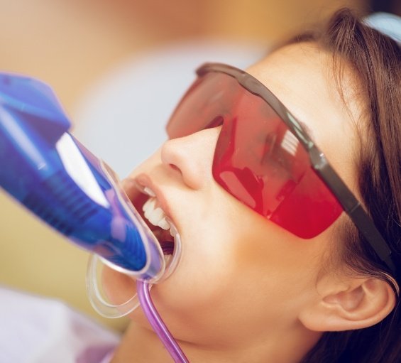 Young woman in dental chair with fluoride trays on her teeth