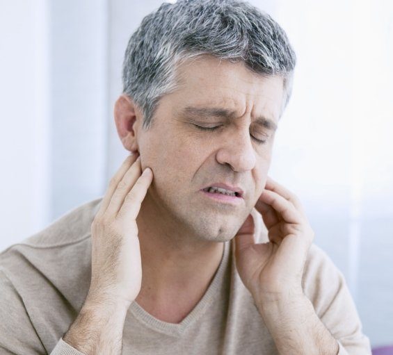 Man touching the sides of his jaw in pain