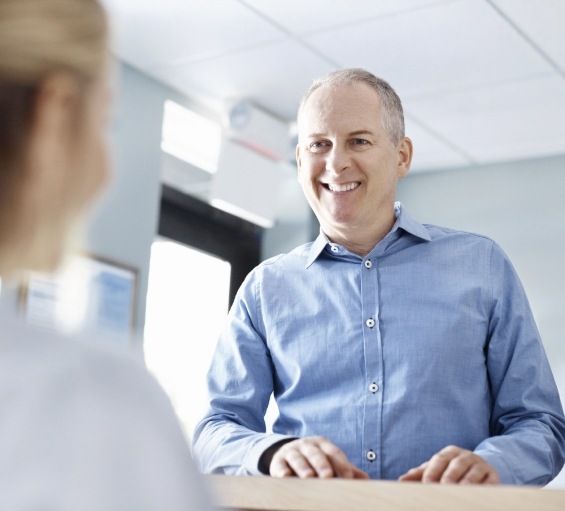 Man smiling at receptionist in Windham dental office