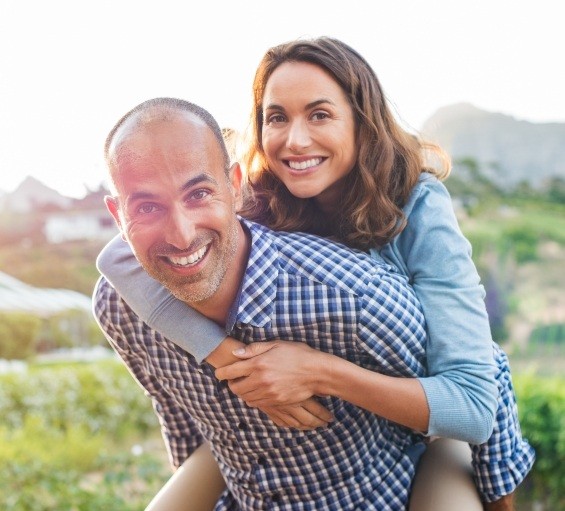 Man and woman smiling outdoors after restorative dentistry in Windham