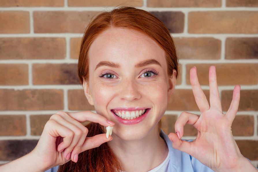 A woman holding an extracted tooth